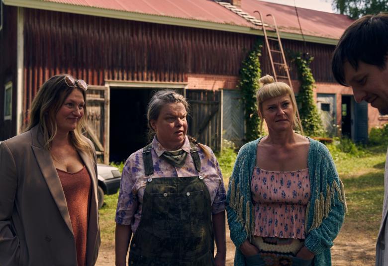 Kuvassa ovat Ria Kataja, Tuija Knihtilä ja Pirjo Lonka seisomassa pihalla, jossa on taustalla punainen navetta. He juttelevat Jakkob Öhrmanin kanssa, joka on osittain selin oikealla.