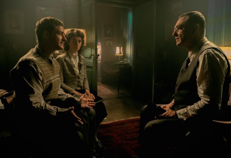 Kuvassa on vasemmalla nuori mies istumassa ja vastapäätä istuu Ville Virtanen. Kuvan sävy on tumman ruskea.