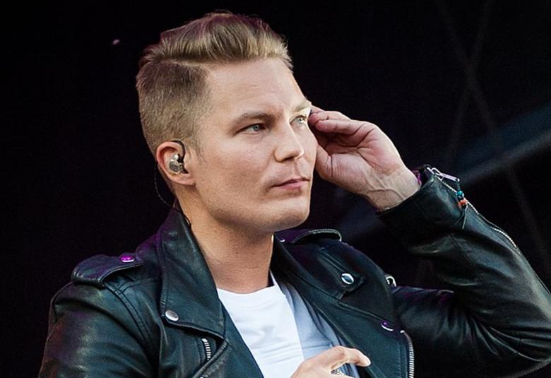 Kuvassa on puolittaisessa sivukuvassa Cheek, joka pitää vasemmalla kädellään kuuloketta korvallaan. Hänellä on lyhyet hiukset ja musta nahkatakki päällään.  Tausta on musta.