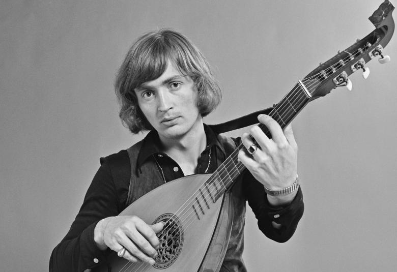 Kuvassa on Jukka Kuoppamäki, jolla on luuttu kädessään ja siinä on pitkä kaula. Kuva on musta-valkoinen. Hänellä on päällään musta paita.