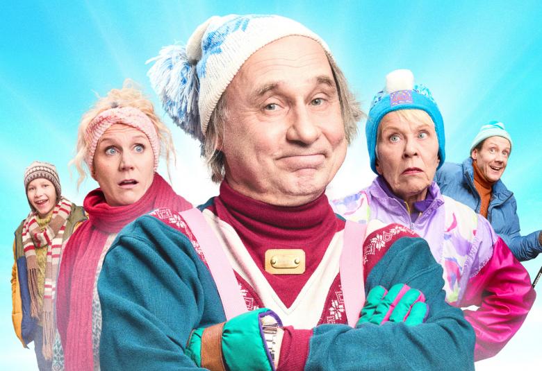 Kuvassa on etualalla Tom Lindholm ja hänellä on turkoosi urheilupusakka ja valkoinen pipo päässään. Olkapään takana näkyy vasemmalla tytär punertavassa pusakassa ja vaaleassa pipossa sekä oikealla olkapään takana saman värissä vaatteissa Tuija Ernamo. Molemmilla puolilla näkyy heidän takanaan henkilöt. Kuva on osa julisteesta.