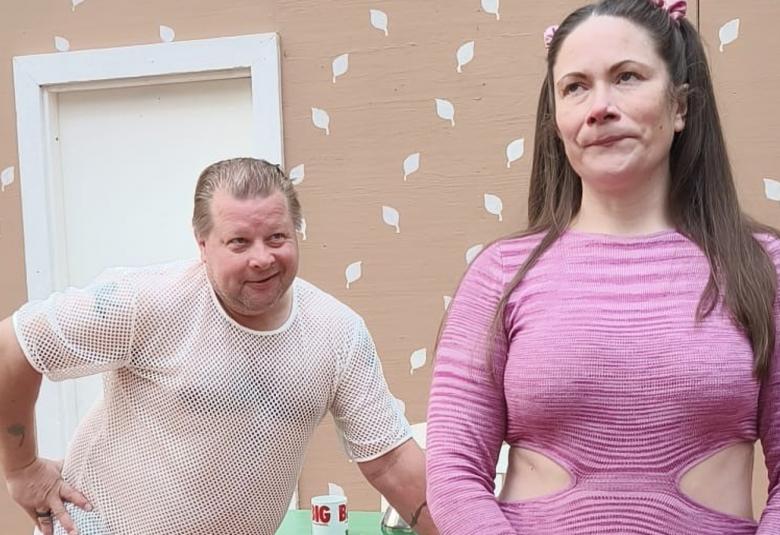 Kuvassa on vasemmalla mies valkoisessa verkkopaidassa ja nojaa eteenpäin. Edessä nainen kilassa paidassa.  Taustalla vaalean ruskeata tapettiseinää, jossa on valkoisia lehtiä.