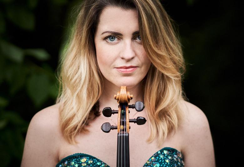 Kuvassa on Anna-Liisa Bezrodny puolivartalokuvassa ja hänellä kädessään on viulu pystysuunnassa, joka nojaa leukaan. Hänellä on avara puvun yläosa, jossa on kaaret rintojen yläpuolella tumman sinisessä puvussa.