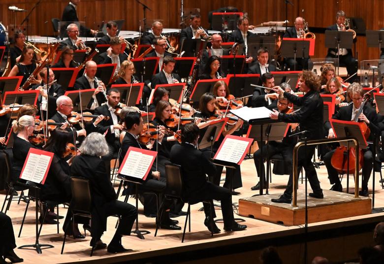 Kuvassa on Philharmonia Orchestra lavalla soittamassa tummissa puvuissa.