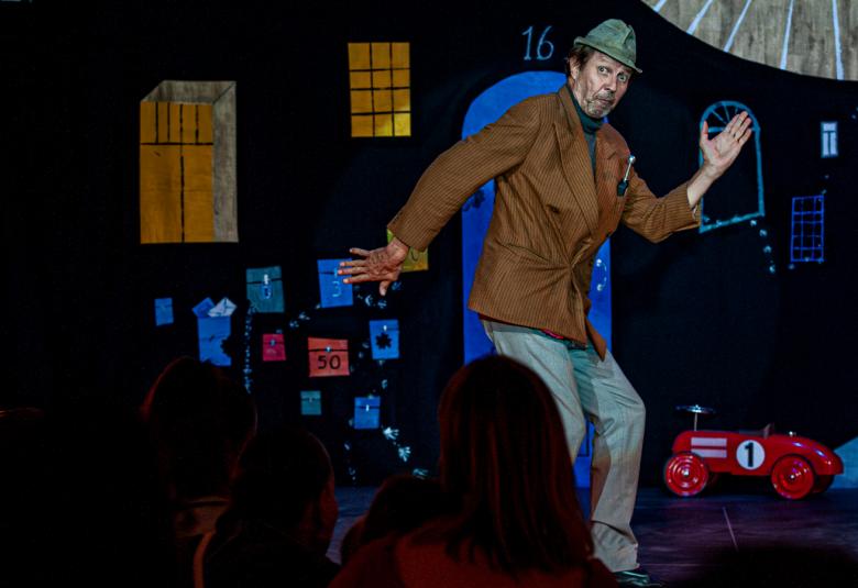 Kuvassa on Erkki Saarela puolivartalokuvassa. Hänellä on tumma college-paita ja pyöreä, punainen tekonenä.  Taustalla on tummanpunainen verho.