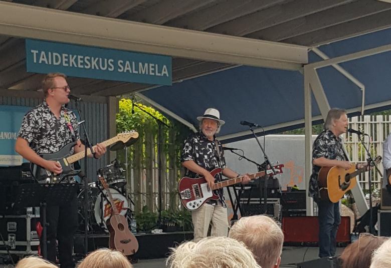Kuvassa on Salmelan lavalla soittamassa kitaraa Tomi Juusela, hänestä oikealle Petteri Kokljuschkin kitarassa, Roni Kamras akustisessa kitarassa ja Lauri Holopainen kitarassa. Taustalla näkyy ylhäällä Taidekeskus Salmela -kyltti. 
