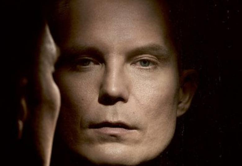 Kuvassa on Jare Tiihonen kasvokuvassa ja vasemmalla takaapäin puoliksi silhuettinä. Kuvan sävy on ruskehtava ja osa kirjan kannesta.