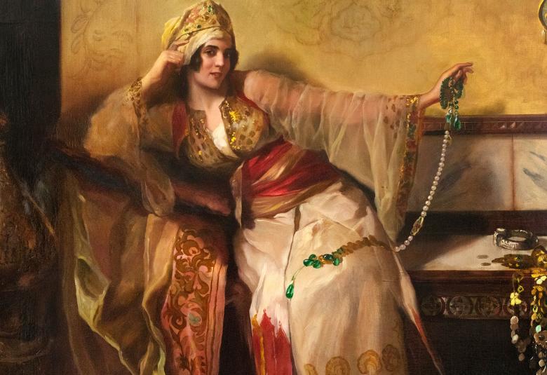 Kuvassa on nuori nainen sohvalla ja nojaa oikealla kädellään käsinäjaan. Hänellä on kultaisen kirjailtu päähine ja hameen ylläosa sekä punainen huivi vyötäröllä. Hameen alaosa on vaalea. Vasemmalla on iso kuparin värinen karahvi ja oikealla vaaleata sohvaa.