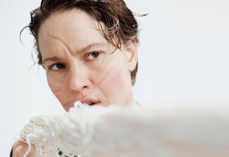 Kuvassa on SEidi Haarla kasvokuvassa ja hänellä on lyhyet, tummat hiukset.  Hän vetää edessään olevaa vaaleaa harsoa.