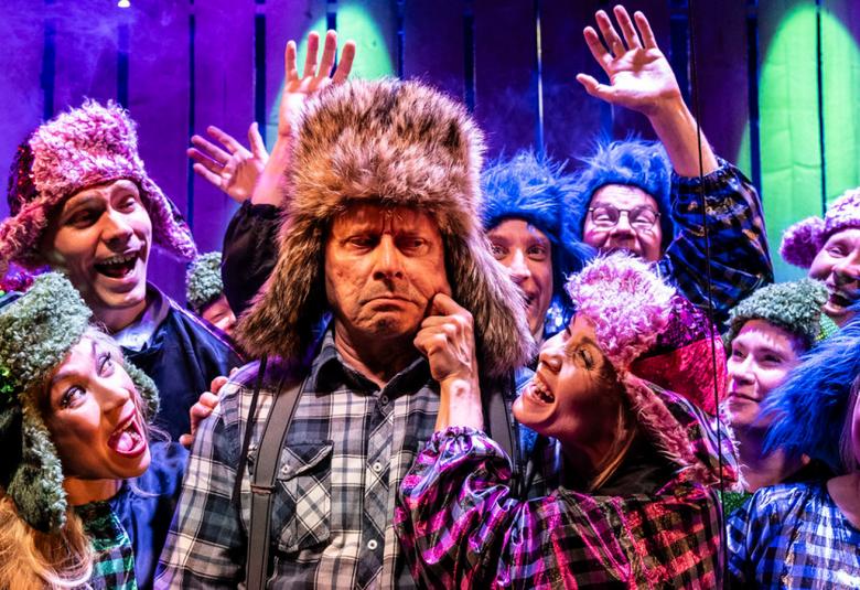 Kuvassa on Jukka-Pekka Löhönen keskellä karvahatussa ja ruutupaidassa. Häntä nipistää poskeen Tiina Räsänen vasemmalla kädellään ja hänellä on myös karvahattu. Ympärillä on monia henkilöitä ja kaikilla on karvahattu päässään. He virnistelevät ympärillään Kihlströmin esittämälle Mielensäpahoittajalle.