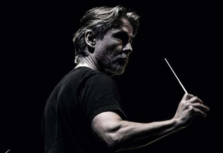 Kuvassa on Esa-Pekka Salonen puolivartalokuvassa johtamassa orkesteria. Hänellä on tahtipuikko kädessään ja hänellä on musta t-paita päällään. Kuvan tausta on musta ja kuva on musta-valkoinen. Kuva on osa kirjan kantta.