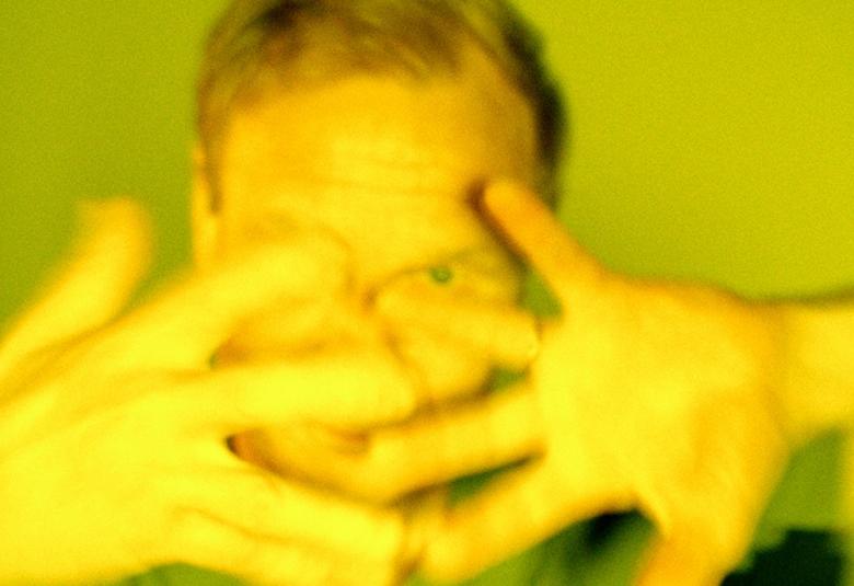 Kuvassa on Ismo Alanko kasvokuvassa ja hänellä on sormet haristettuna kasvojen edessä. Kuvan sävy on vihertävä.