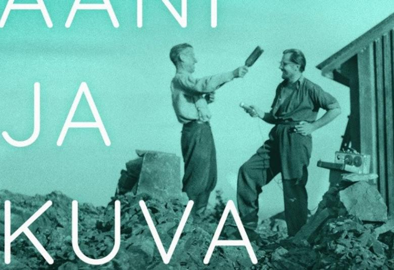 Kuvassa on vaalean vihreällä pohjalla musta-valkokuvassa kaksi miestä juttelemassa iloisesti vastakkaine ja vasemmalla ojentaa oikealla kädellään pulloa toista miestä kohti. Takana oikealla on varastorakennusta. Miehet seisovat rakennuksen raunion päällä.