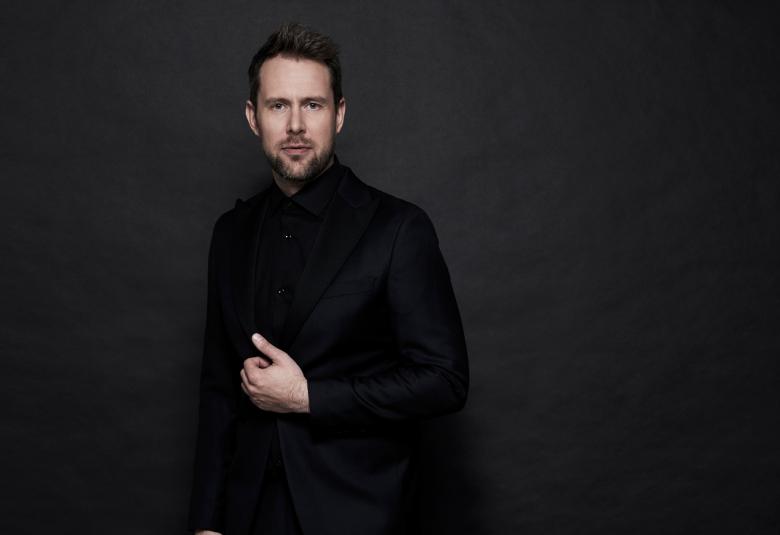 Kuvassa on Waltteri Torikka tummassa kuvassa, jossa hän seisoo hänestä näkyy kasvot sekä oikea käsi. Hänellä on mustat vaatteet.