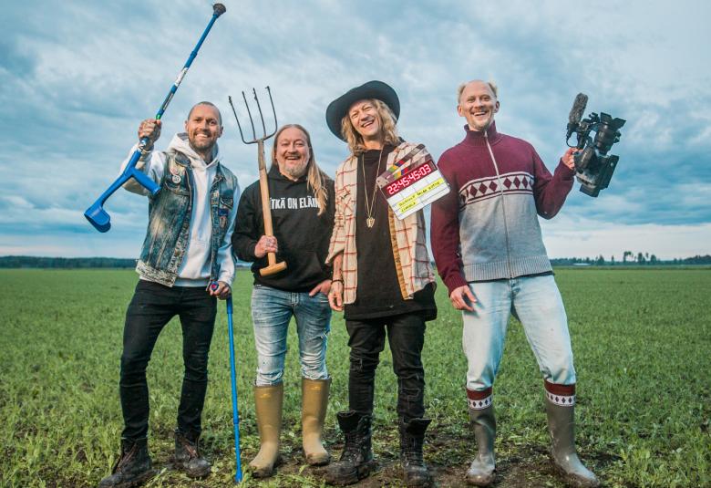 Kuvassa ovat Duudsonien neljä miestä ja heillä on erilaisia työvälineitä kädessään kuten talikko ja golfmaila. Heillä on eri värisiä farkkuja ja puseroita päällään. Taustalla on sini-valkoista taivasta ja alla vihreää heinäpeltoa.