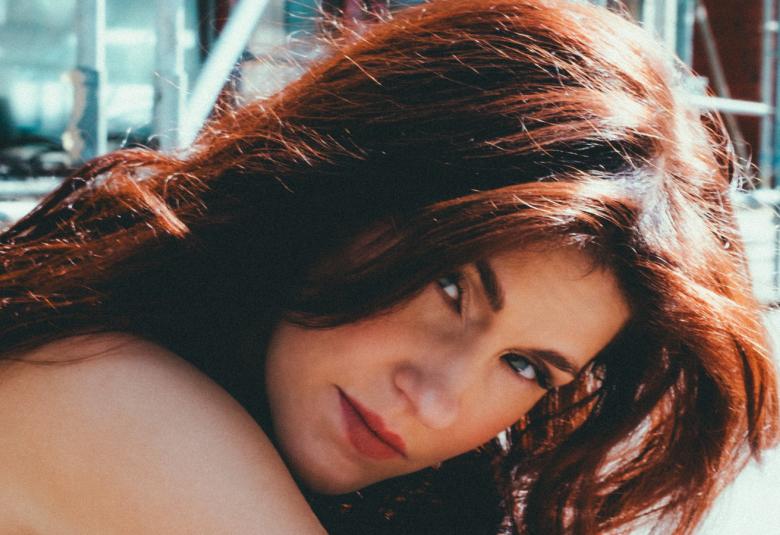 Kuvassa on Jannika B sivuttain kumartuneena.  Hänellä on punertavan ruskeat hiukset. 