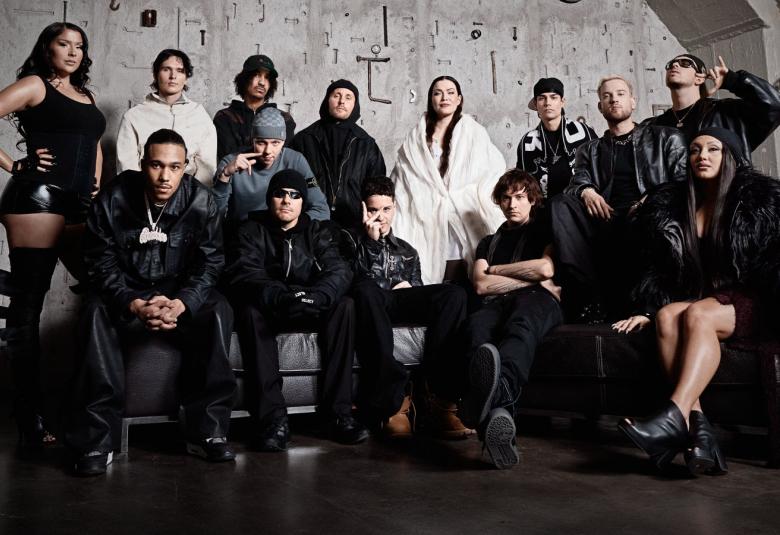 Kuvassa on kahdessa rivissä artistit ja takana on kahdeksen mies ja naisartistia, edessä viisi istumassa. Heillä on mustat vaatteet paitsi kadella valkoiset.