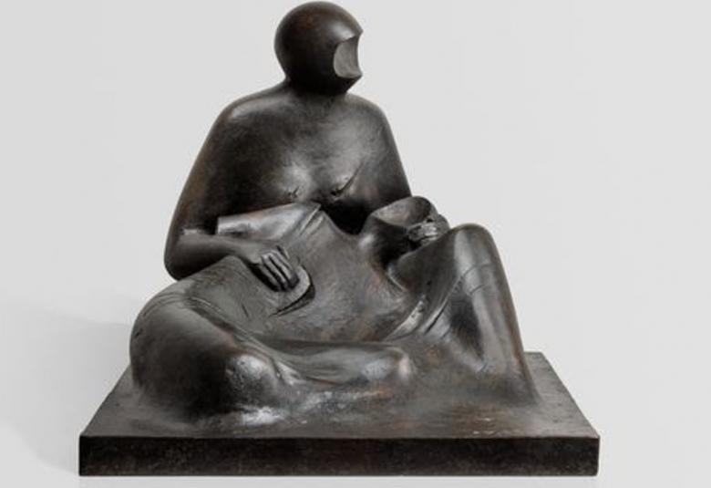 Kuvassa on veistos, joka on musta ja siinä on kasvot koverrettu naishahmo istumassa ja pitelemässä toista ihmishahmoa, joka on makuuasemmossa hänen sylissään. Kuva on musta-valkoinen.