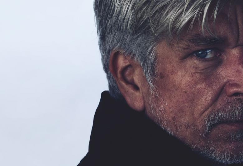 Kuvassa on Karl Ove Knausgård oikeassa laidassa kasvokuvassa.  Hän on hieman vinottain ja kasvojen sävy on tummahko. tausta on harmaa.