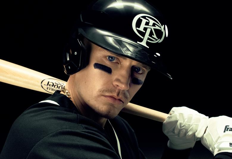 Kuvassa on puolivartalokuvassa Gettomasa mustassa kypärässä ja hän pitää olkapäällään vaaleaa pesäpallomailaa. Hänellä on musta pusero päällään ja tausta on musta.