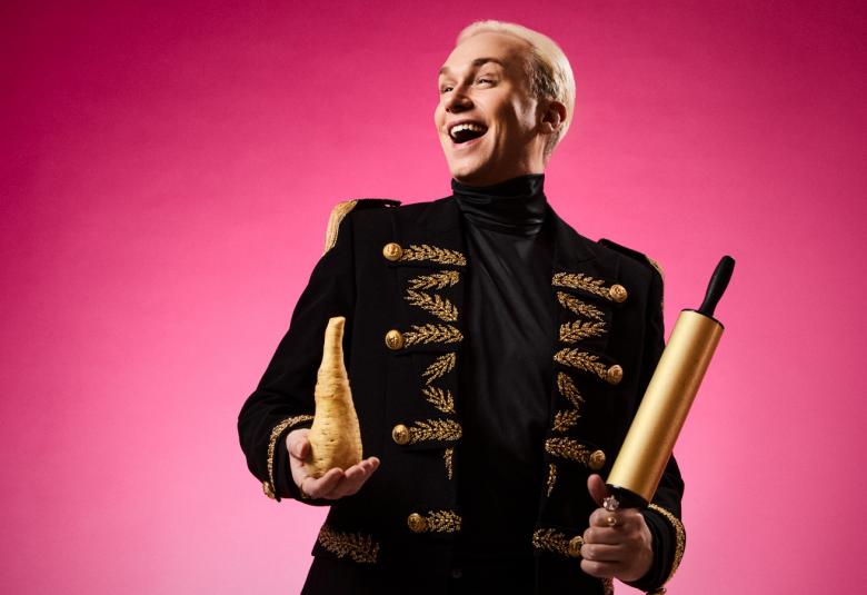 Kuvassa on Christoffer Strandberg puolivartalokuvassa. Hänellä on musta takki, jossa on kultaiset plamikkorivit, joissa on nappeja. Oikeassa kädessä on kullan värinen pieni maljakko ja vasemmalla kullan värinen kaulin. Tausta on pinkki. 