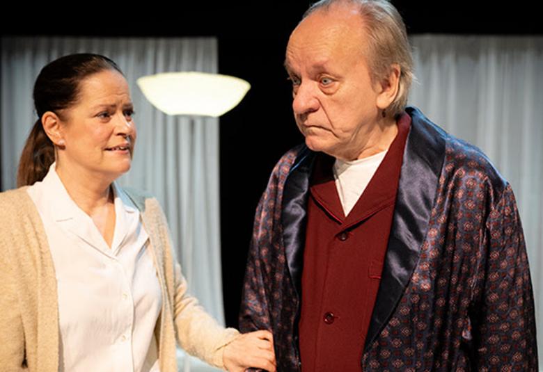 Kuvassa on vasemmalla Miia Selin valkoisessa paitapuserossa ja kellertävässä villatakissa.  Hänen oikealla puolellaan on Esko Roine kiiltävässä aamutakissa ja tumman punaisessa villapaidassa. He seisovat puolivartalokuvassa olohuoneessa.