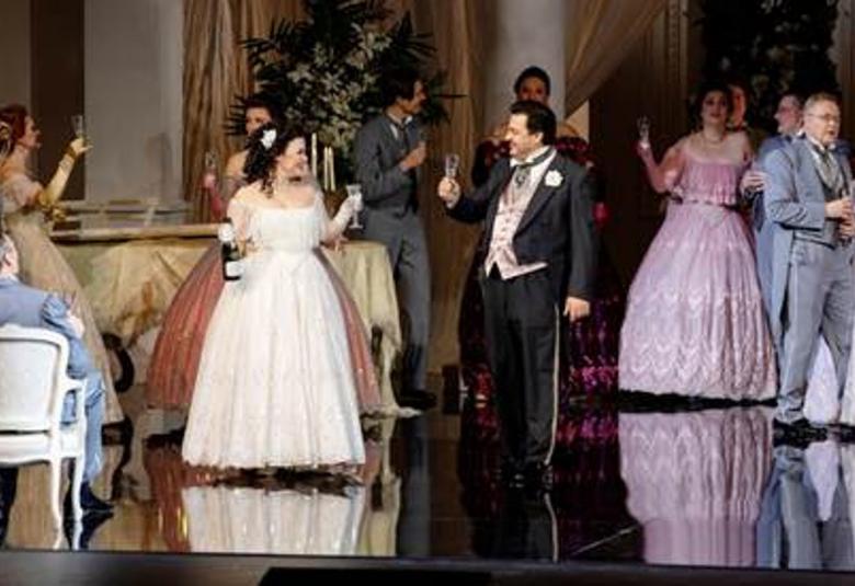 Kuvassa on pitkissä, leveä helmaisissa puvuissa ja frakeissa juhlivia ihmisiä ja he nostelevat maljoja seisoessaan.  