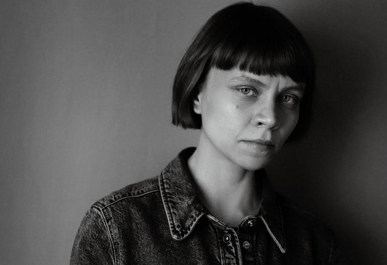 Kuvassa on Mariia Niskavaara ja hän on puolivartalokuvassa. Hänellä on farkkutakki päällään. Tausta on tumma. Kuva on musta-valkoinen.