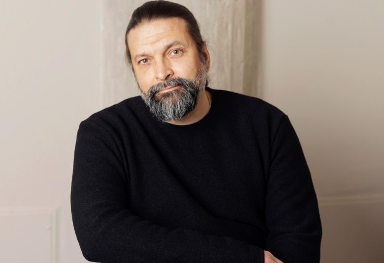 Kuvassa on Riku Saatsi puolivartalokuvassa ja hänellä on musta paita päällään. Tausta on harmahtava.