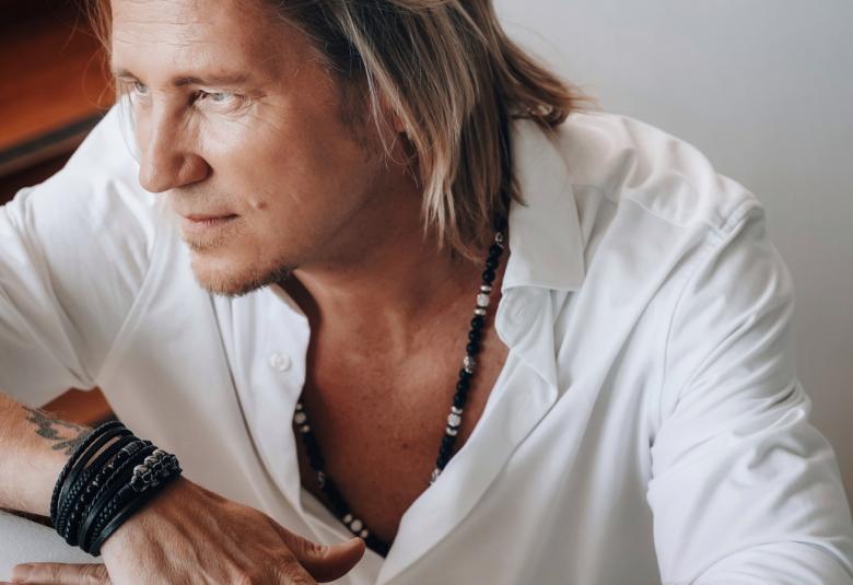 Kuvassa on Sami Kuronen valkoisessa paidassa istumassa vinottain vasemmalla puolivartalokuvassa hieman yläviistosta. 