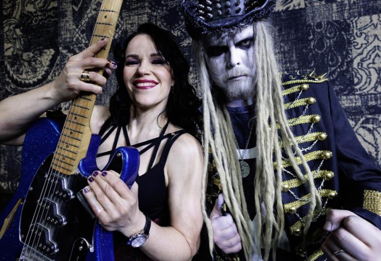 Kuvassa on vasemmalla Erja Lyytinen hihattomassa,  mustassa t-paidassa ja edessään käsissään pystyssä olevaa sini-mustaa kitaraa, jossa on ruskea kaula. Oikealla on King Satan, jolla on pitkät vaaleat hiukset ja päässään nastoilla varusettu musta stetson. Hänellä on päällään kultapunostakki. Taustalla on tumman kirjavaa kangasta. 