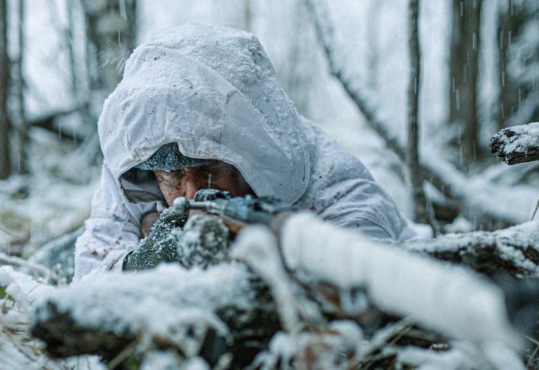 Kuvassa on Jarkko Lahti lumihangessa tähtäämässä eteenpäin ja kuva on lähikuva edestä päin. Taustalla on lumista metsää.  
