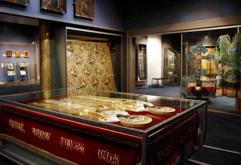 Kuvassa on museon kulmaa, jossa on tumman puun keskellä sekä ikoneja että muita teoksia. Keskellä on tummaa puuta oleva pöytä ja sen päällä kaksi kultaista hahmoa kantena.