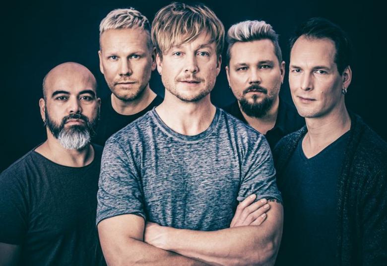 Kuvassa ovat Sunrise Avenuen viisi miesjäsentä puolivartalokuvassa. Muilla on mustat t-paidat, mutta keskellä on Samu Huber, jolla on sininen t-paita. Tausta on musta.