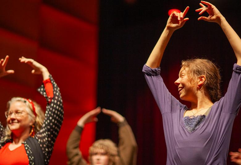 Kuvassa on puolivartalokuvassa kolme flamenco-tanssijaa ja heillä on kädet ylhäällä. Taustalla on punertavaa seinää. 