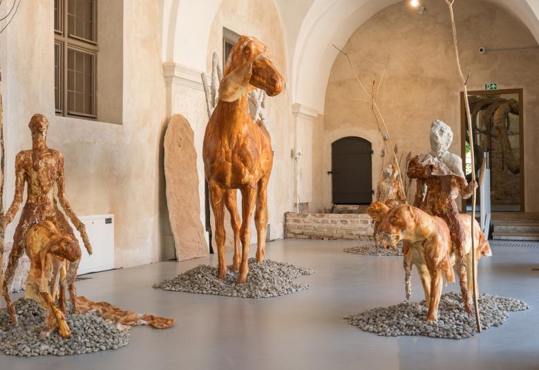 Kuvanveistäjä Edith Karlsonin näyttelyssä kävijä kohtaa nelimetrisiä jättiläisiä, salin ylle kaareutuvan luurangon ja kohti vääjäämätöntä kohtaloaan ratsastavan armeijan. Linnut ja muut eläimet tuijottavat hiljaisina vastaan. Kaivon äärellä lepäilevät merenneidot ovat nousseet vedestä todistamaan, mitä ihminen on merelle ja maalle tehnyt.  Karlsonille tarunomaiset hahmot ovat keino käsitellä kysymyksiä, joita on järkeilemälllä vaikeaa tai mahdotonta ymmärtää. Ihmisiä ja eläimiä yhdistävät vietit, sinnikäs e