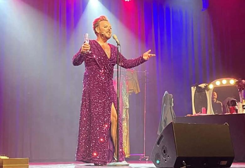 Kuvassa on Mika Tepsä pitkässä punaisessa glittermekossa. Hän laulaa mikin ääressä kädet ojennettuina ja sampanjalasi oikeassa kädessään. Taustalla on punaisella ja sinisellä valaistua seinää.