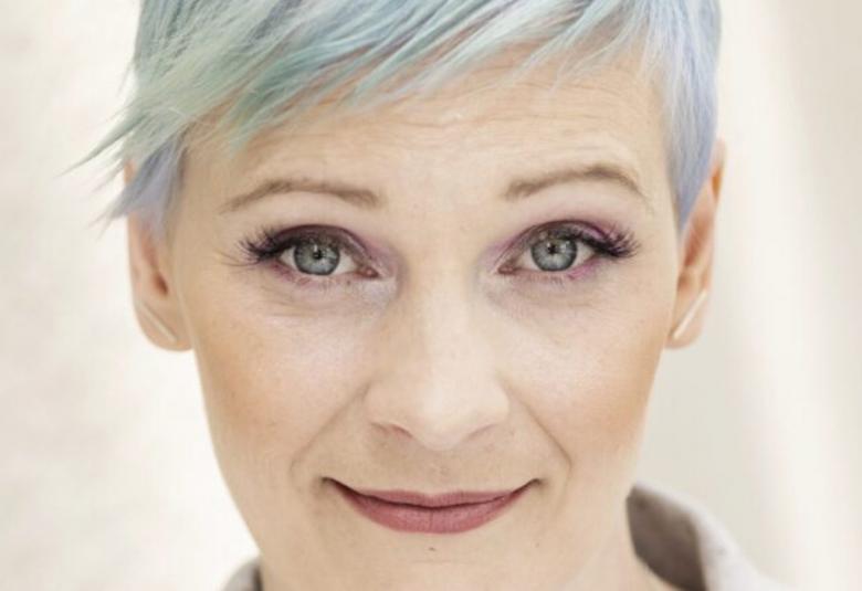  Kuvassa on Annukka Salama kasvokuvassa ja hänellä on sinertää lyhyissä hiuksissaan. Tausta on vaalea.