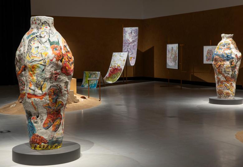 Kuvassa on vasemmalla iso värikäs ruukku ja oikealla taaempana toinen. Takana on liukumäkimäinen ja kaksi jyrkkää ylämäkeä.