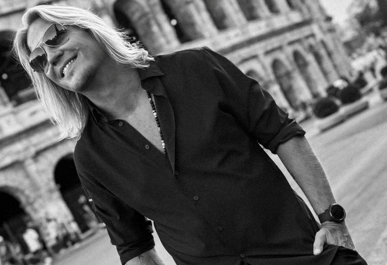 Kuvassa on Sami Kuronen kuvattuna vinosti Colosseumin edessä. Hänellä on musta paita päällään. Kuva on musta-valkoinen.