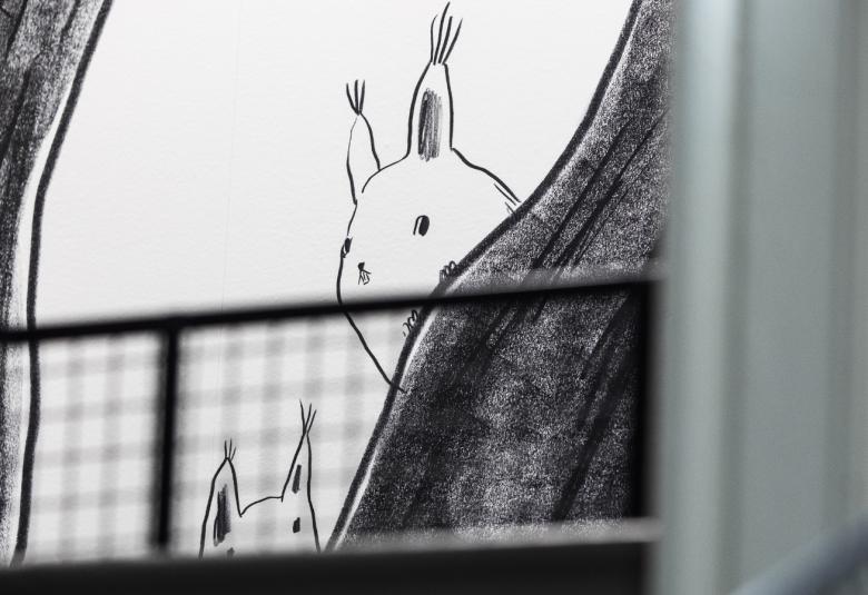 Kuvassa on graafinen teos, joss valkoisella pohjalla kurkkii jänis tumman harmaan verhon takaa. Takaa näkyy ruutuverhoa.
