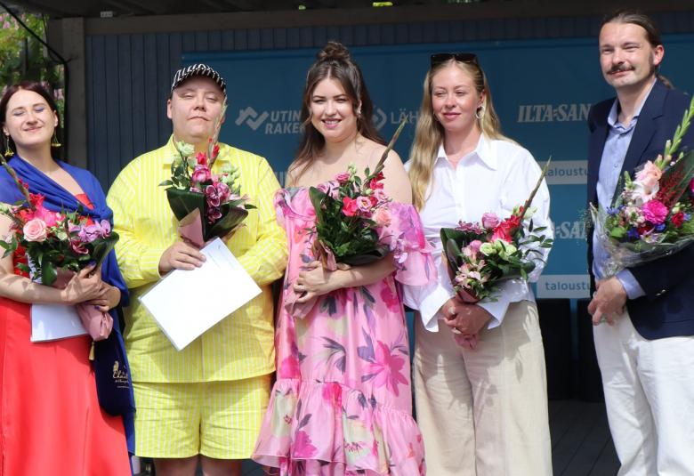 Kuvassa ovat vasemmalta Isa Suoja Rinne punaisessa mekossa, Jone Mutka keltaisessa puserossa ja shortseissa, Aino-Maija Laaksonen vaalean punaisessa kukkamekossa, Iines Niemelä vaaleassa housupuvussa ja Ilkka Aho mustassa takissa ja valkoisessa puserossa.