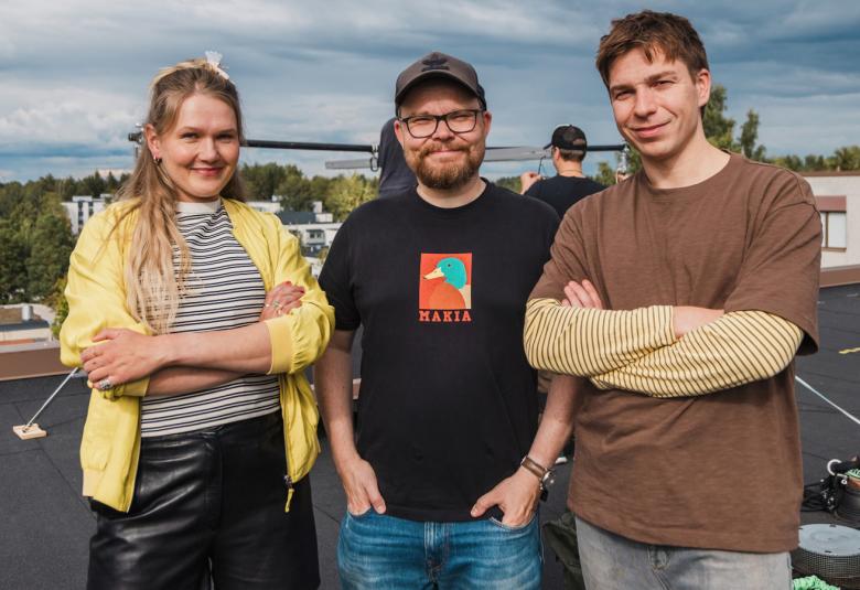 Kuvassa on puolivartalokuvassa ulkona vasemmalla Milla Virtanen keltaisessa villatakissa ja keskellä Antti Heikki Pesonen mustassa t-paidassa. Oikealla on Tom Rejström ruskeassa t-paidassa. 