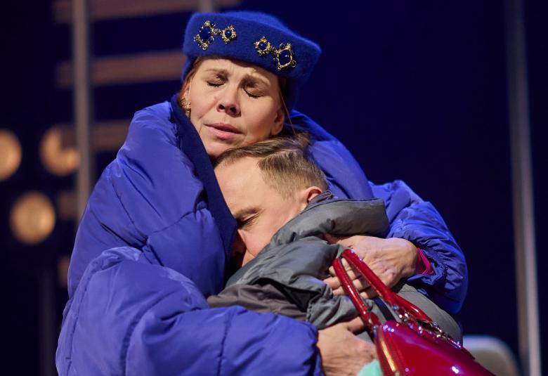 Kuvassa on Eeva Soivio isossa sinisessä toppatakissa ja hän pitää sylissään halauksessa Jarkko Lahtea. 