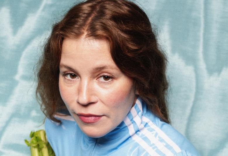 Kuvassa on Viivi Prokofjev kasvokuvassa ja hänellä on vaalean sininen pusero päällään. Hänellä on punaiset pitkät hiukset. Taustalla vaaleaa turkoosia ja valkoista kangasta.