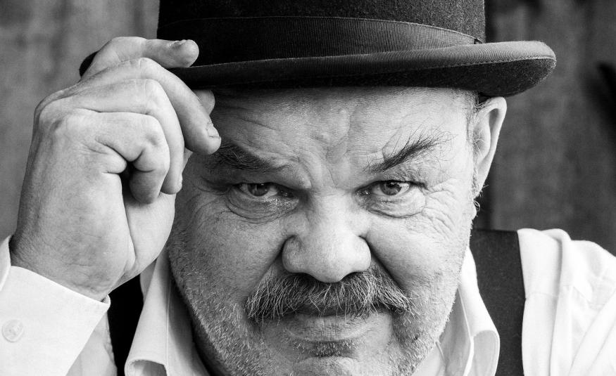 Kuvassa on Jaakko Teppo käavokuvassa ja hänellä on musa lierihattu päässään. Hän pitää oikealla kädellään kiinni hatun lieristä. 