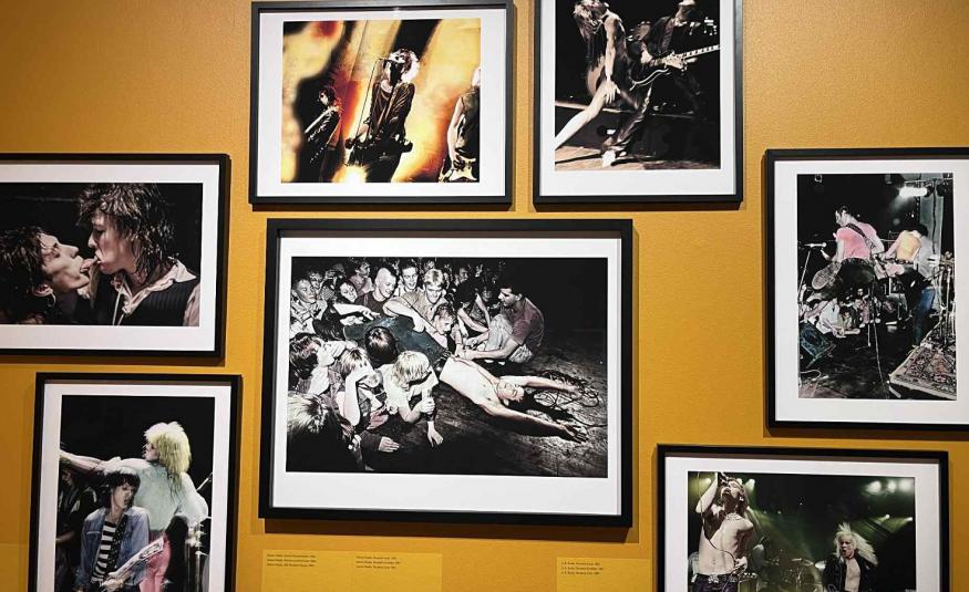 Kuvassa on kellertävällä seinällä musta-valkoisia kuvia. Keskellä olevan ympärillä on kuusi pienempää kuvaa.