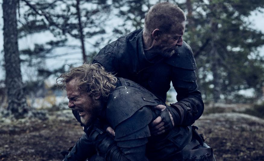 Kuvassa ovat Elias Salonen edessä ja häntä pitää syliotteessa Eero Aho. Taustalla on mäntymetsää.