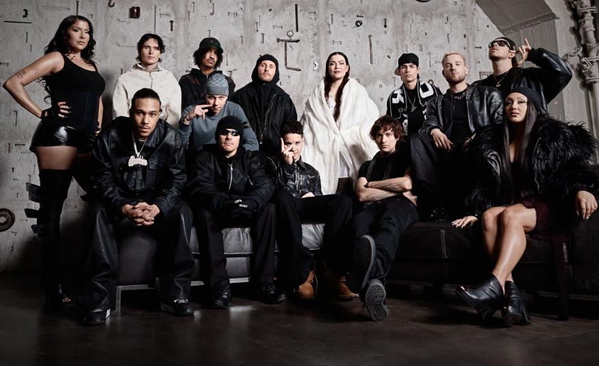 Kuvassa on kahdessa rivissä artistit ja takana on kahdeksen mies ja naisartistia, edessä viisi istumassa. Heillä on mustat vaatteet paitsi kadella valkoiset.