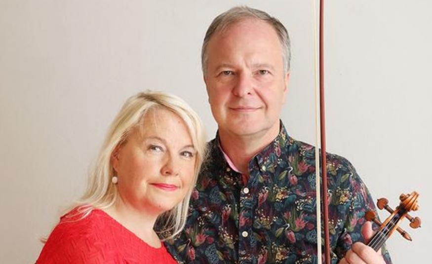 Kuvassa ovat puolivartalokuvassa Anu Komsi punaisessa puserossa ja Sakari Oramo tumman kirjavassa paidassa. Tausta on vaalea.